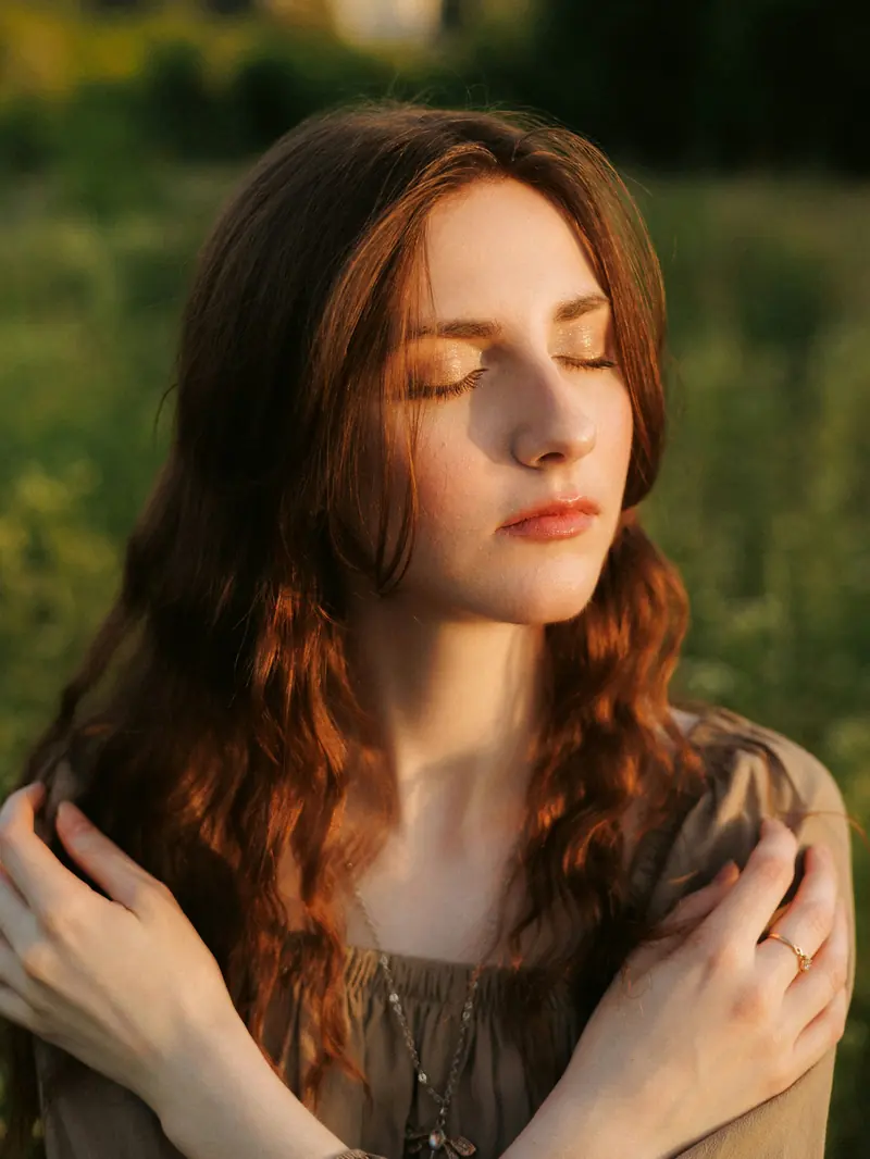 A woman with her eyes closed in warm evening light