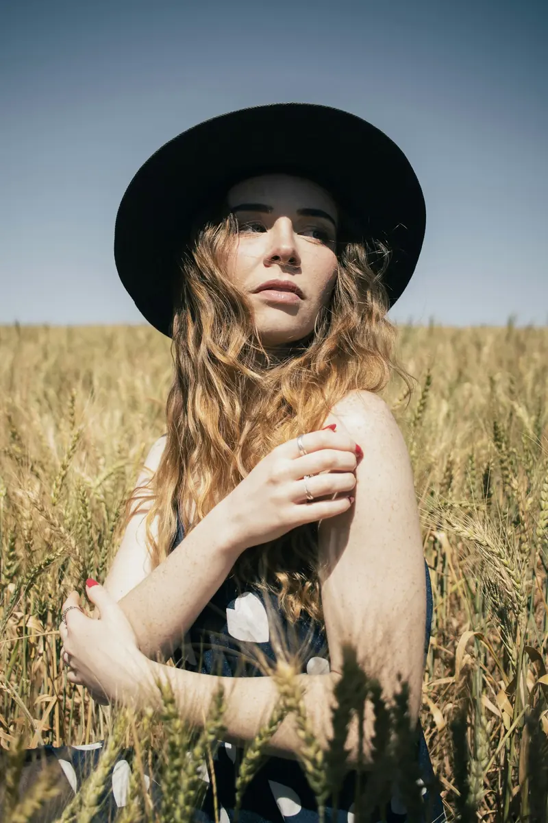 A woman in a black hat standing in a wheat field
