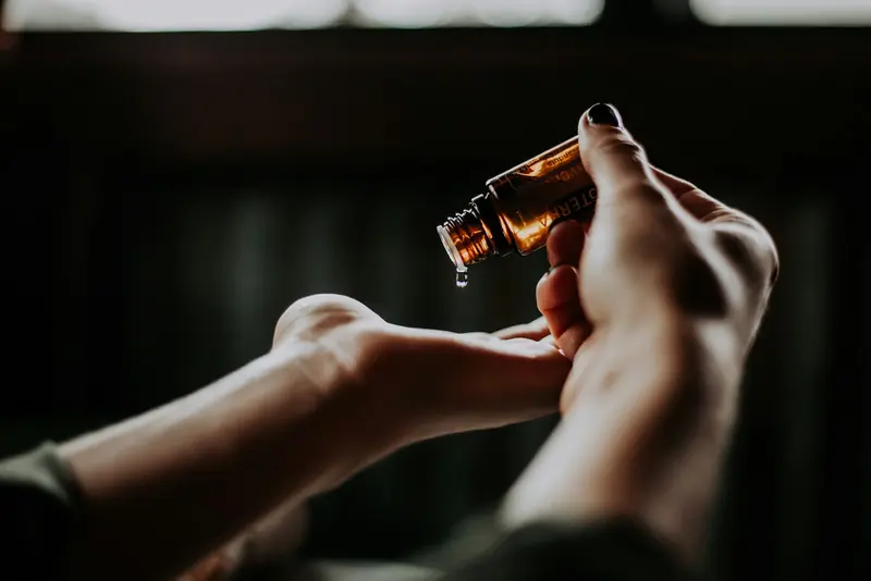Oil dripping from an amber bottle into a palm