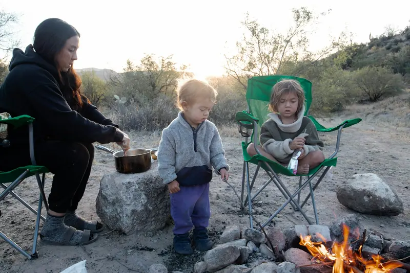 A parent and two kids around a campfire