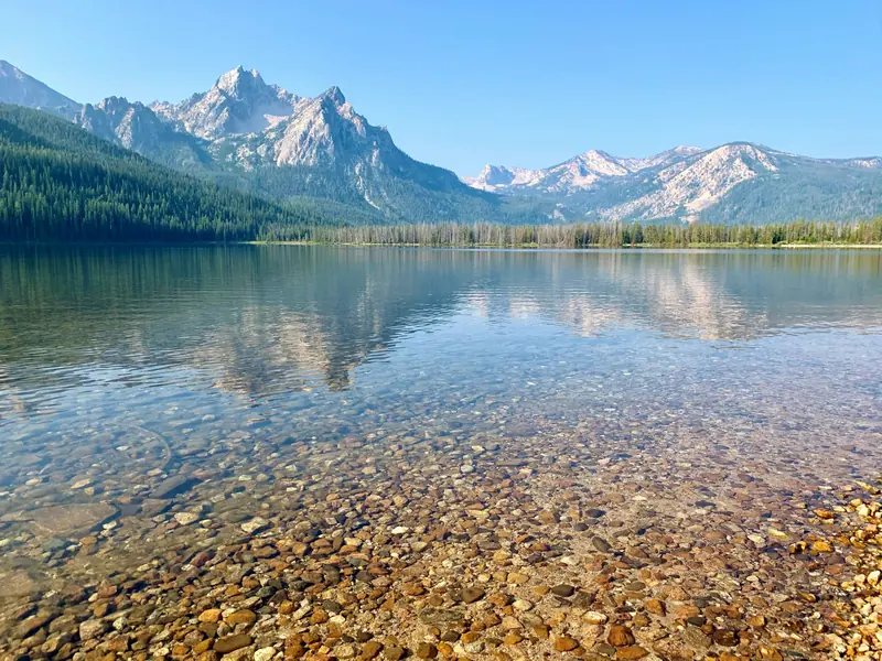 A clear mountain lake with jagged peaks behind it