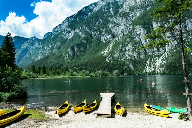 Kayaks pulled up on a beach below the mountains
