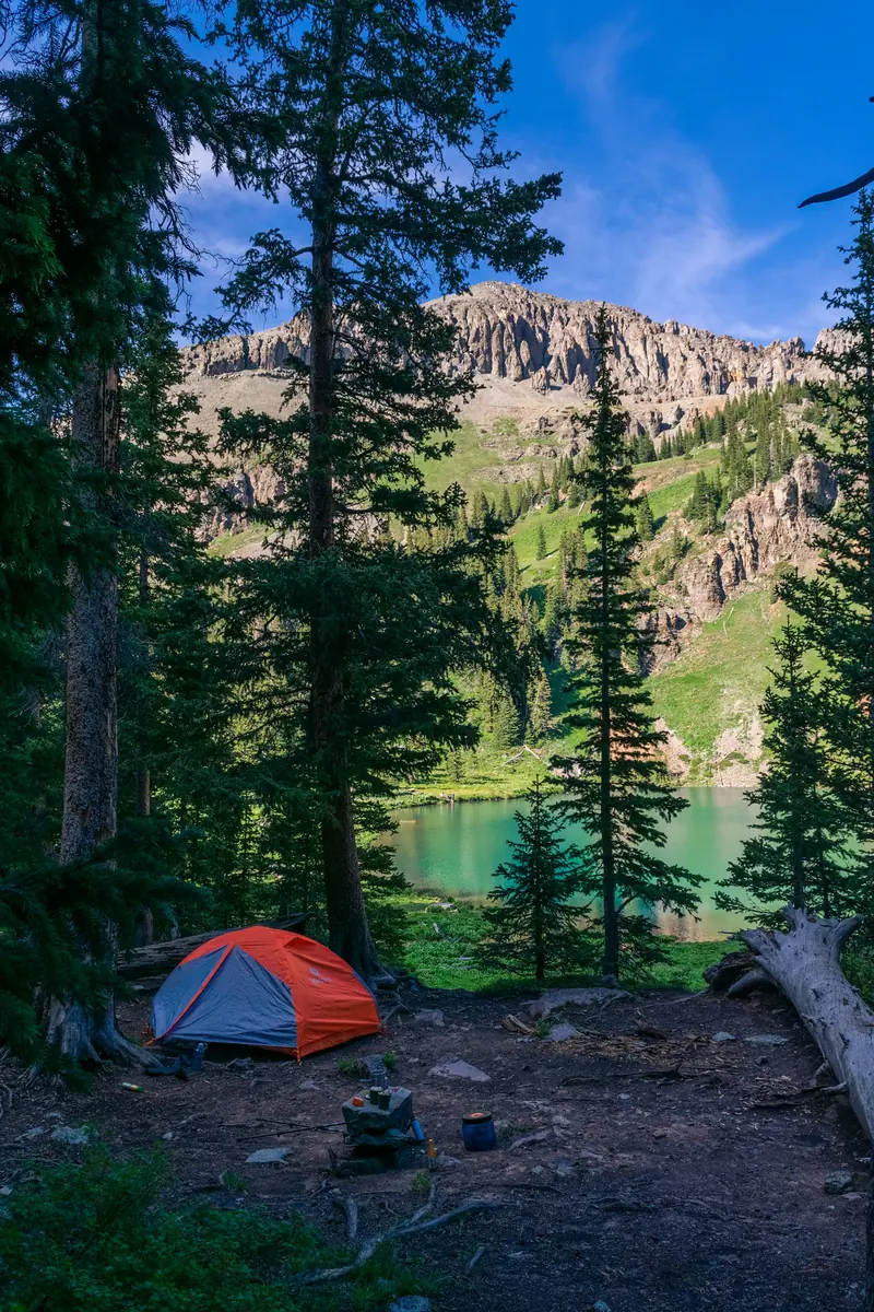 A tent pitched in the woods above a lake