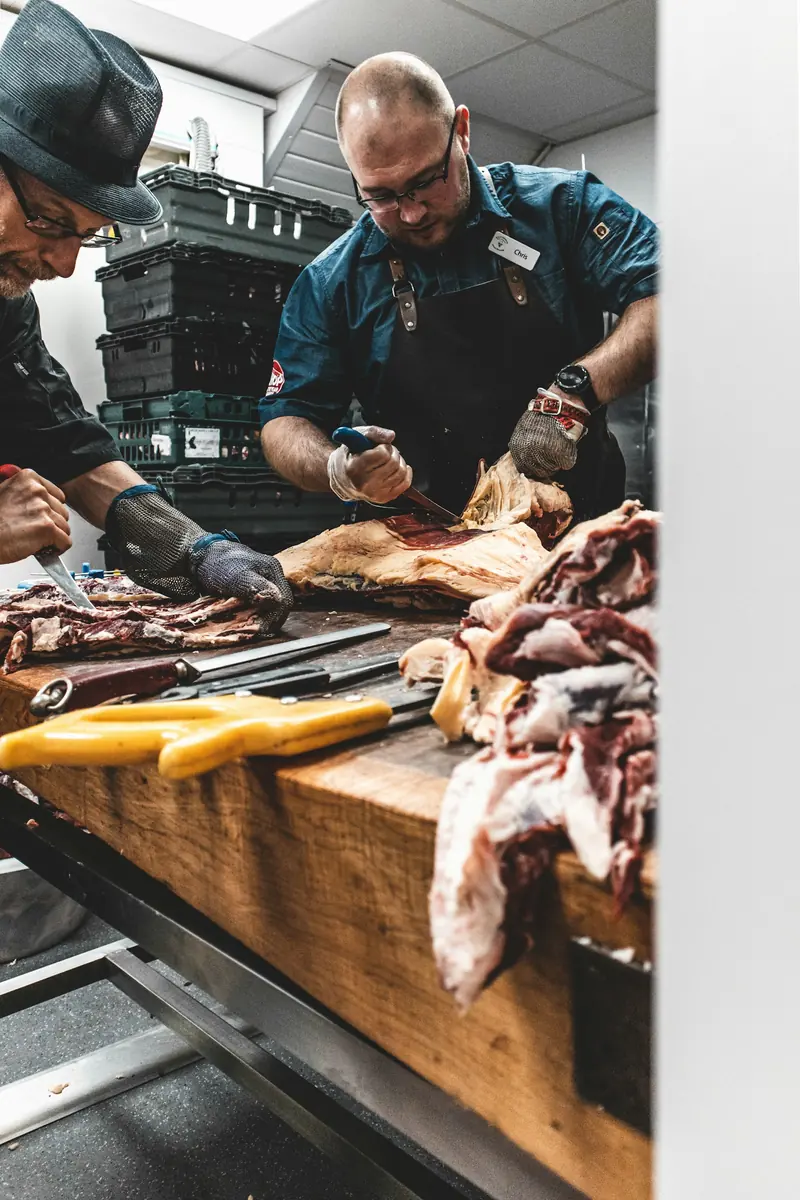 A butcher slicing beef at a wooden counter