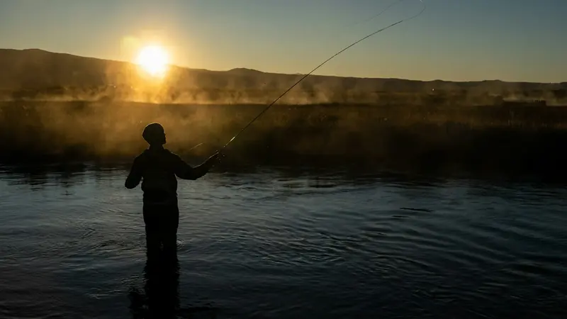 An angler on a lake at sunrise