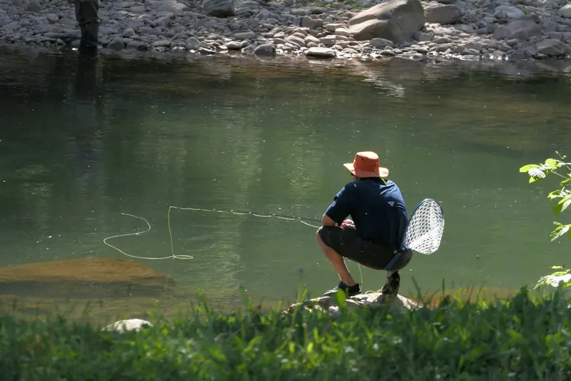 An angler kneeling at the river with a net