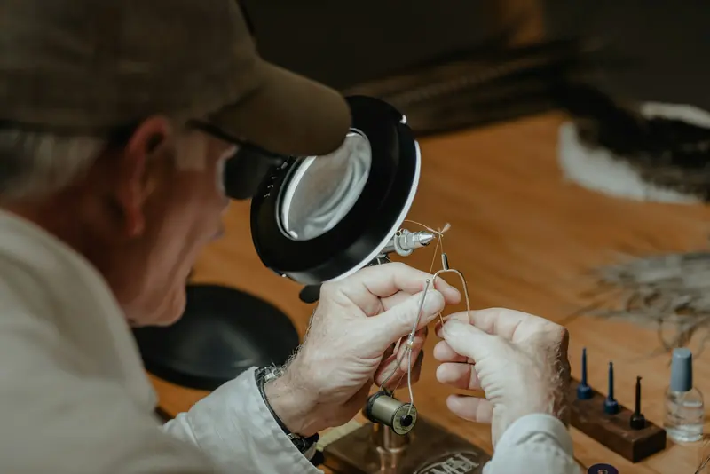 A man tying a fly under a magnifying lamp