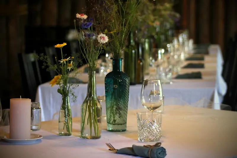 Wildflowers in glass bottles beside a candle
