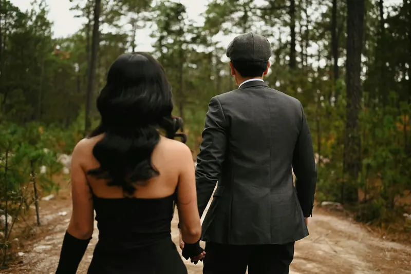 A couple walking hand in hand into the woods
