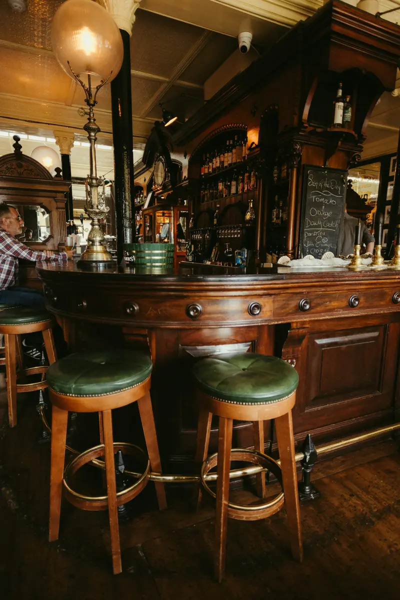 An old wooden bar with green leather stools