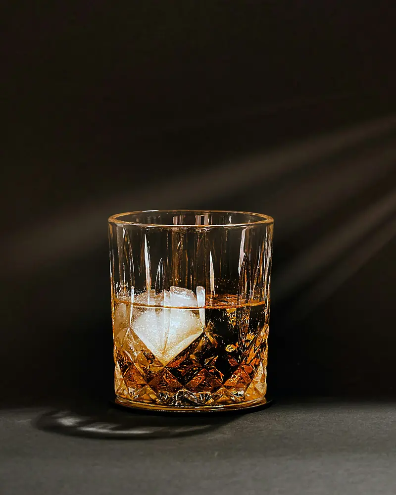 A glass of whiskey with one large ice cube