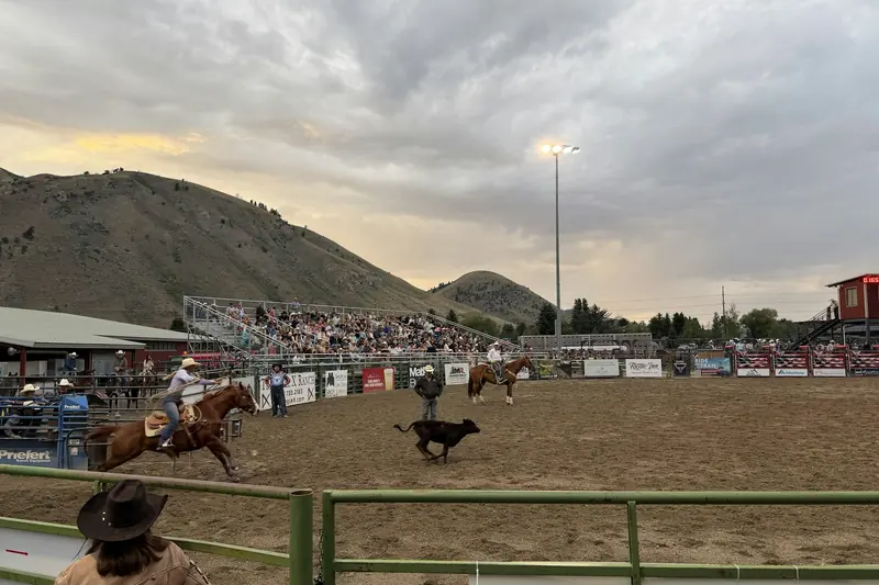 A small-town rodeo arena below rolling hills