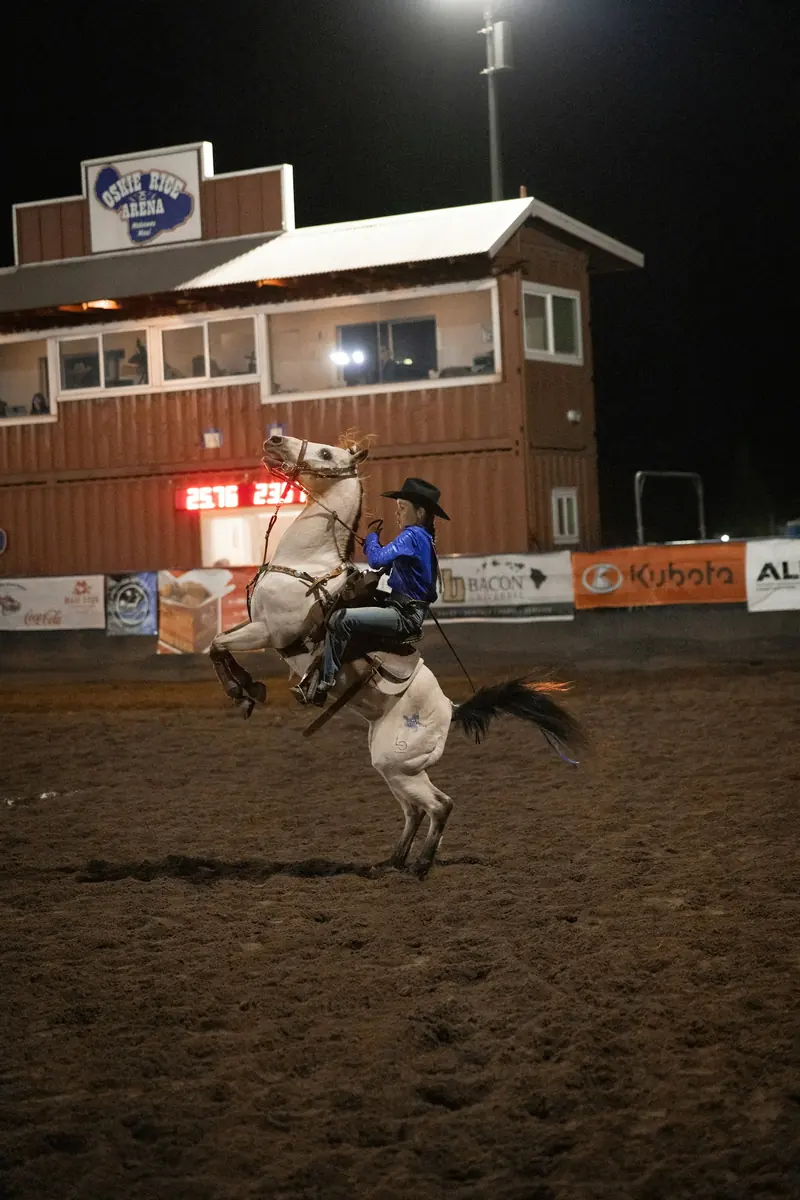 A bronc ride under the lights at a night rodeo