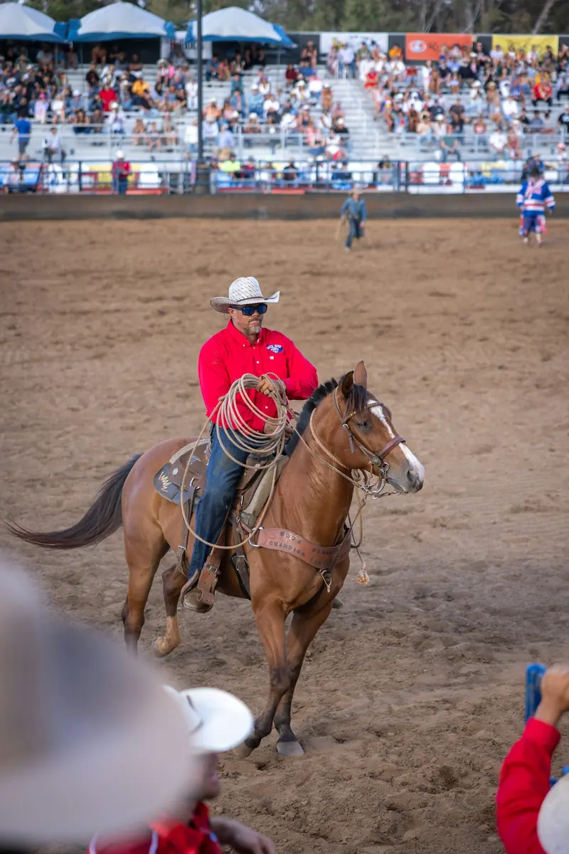 A rider in a red shirt loping across the arena
