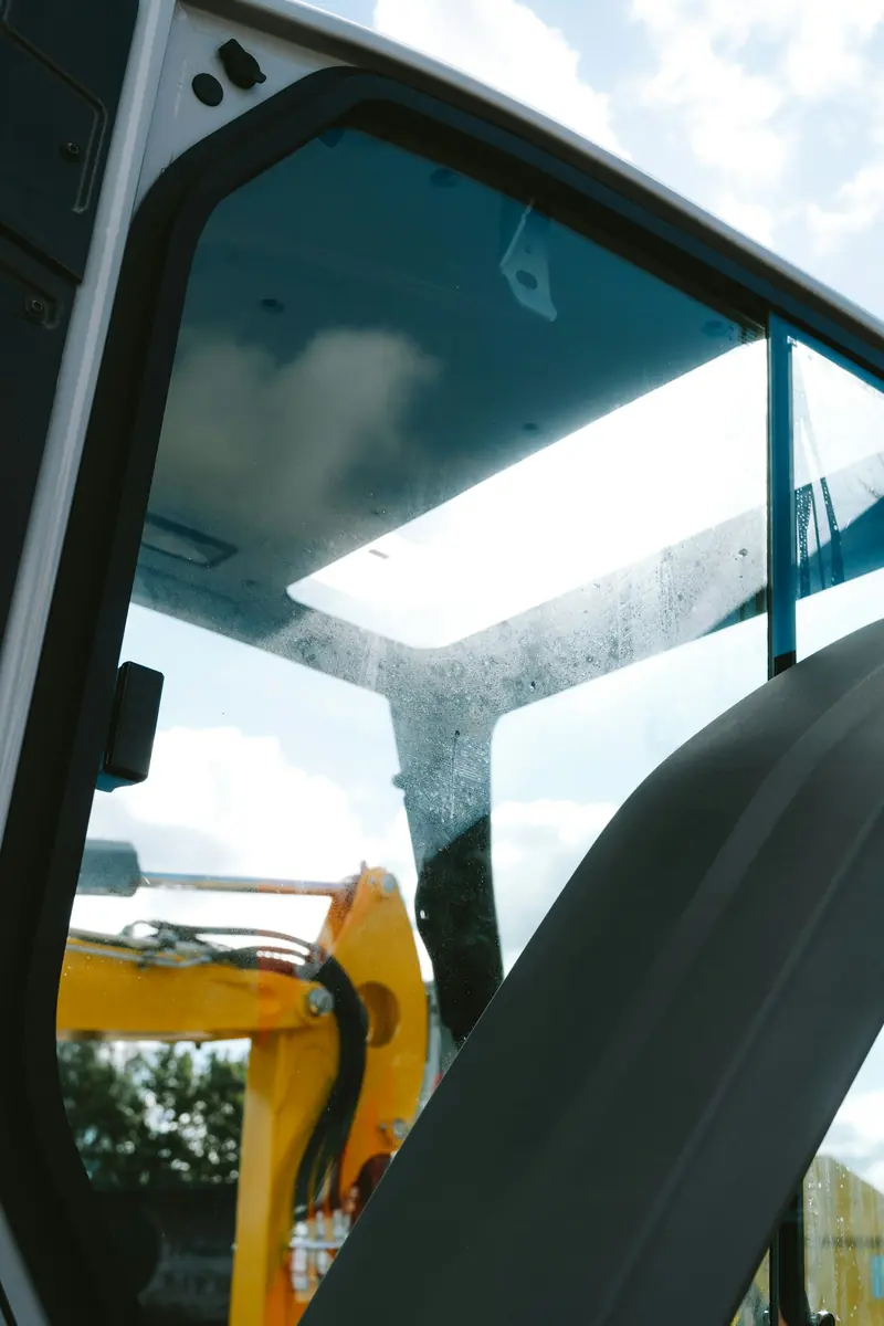A yellow excavator seen through the cab window of another machine