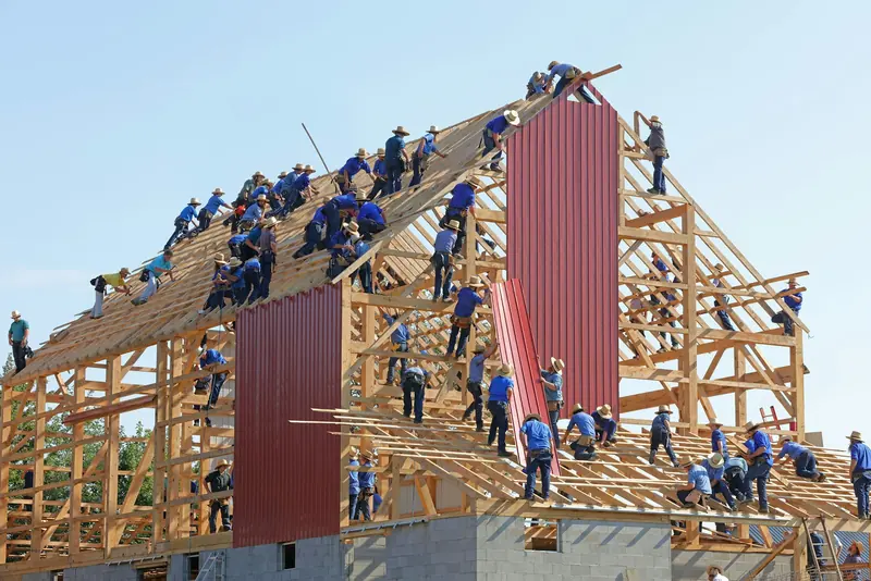 A crew raising the timber frame of a barn
