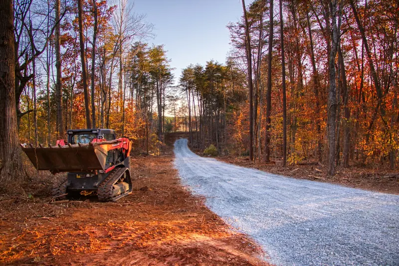 A skid steer on a fresh gravel road in the fall woods