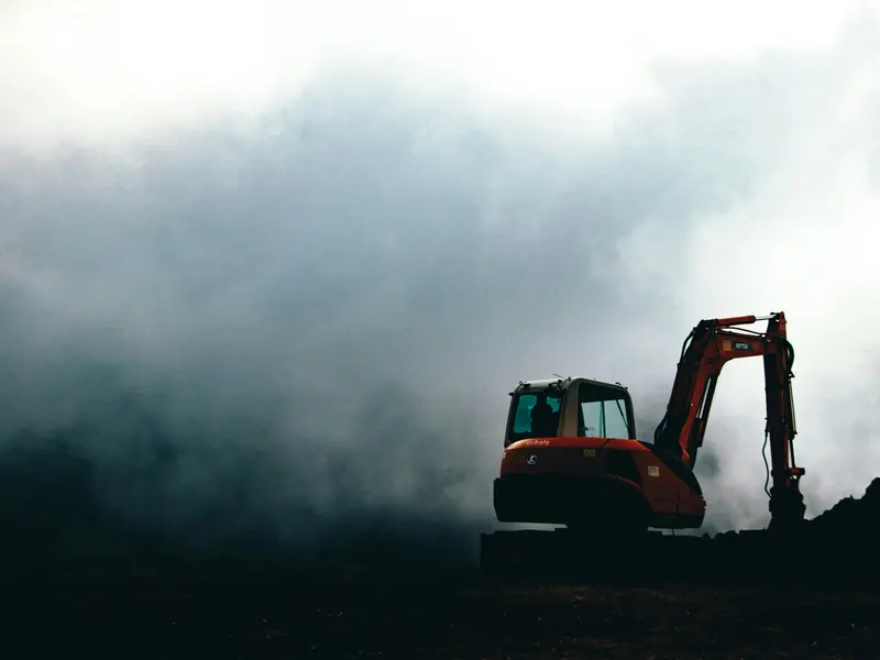 A bulldozer working on a hilltop in heavy fog