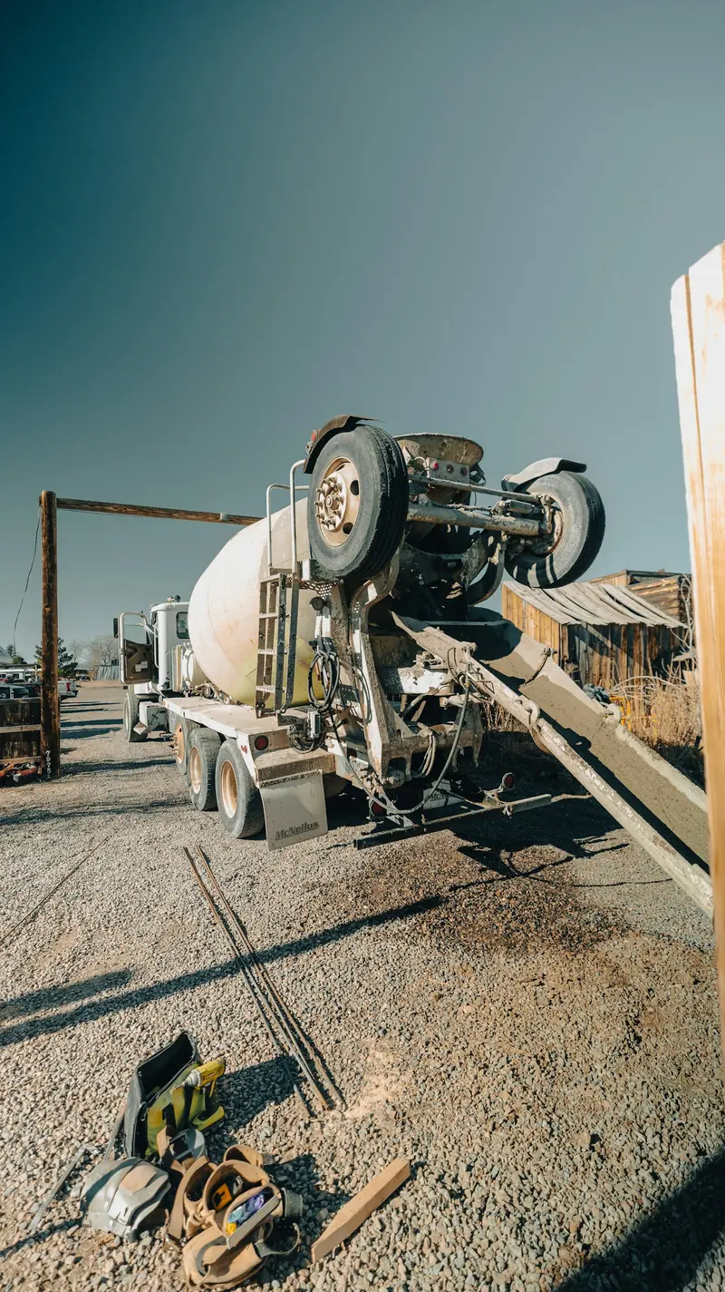 A cement truck pouring with tools laid out on gravel