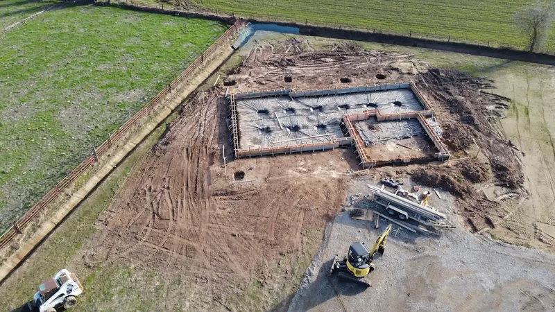 A foundation dug out in a green field from above