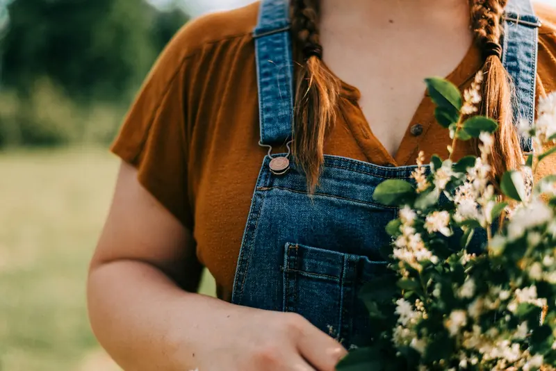A farmer in overalls holding white flowers