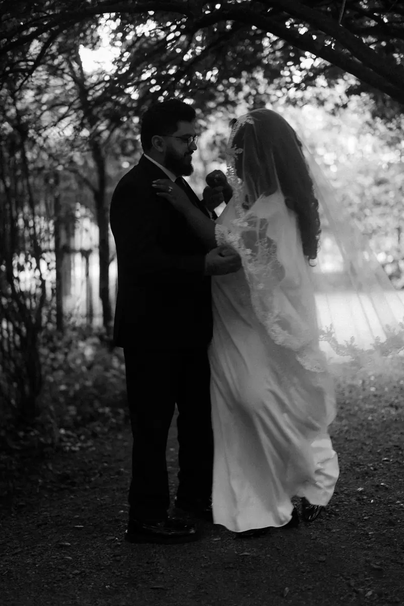 A bride and groom under an archway of trees