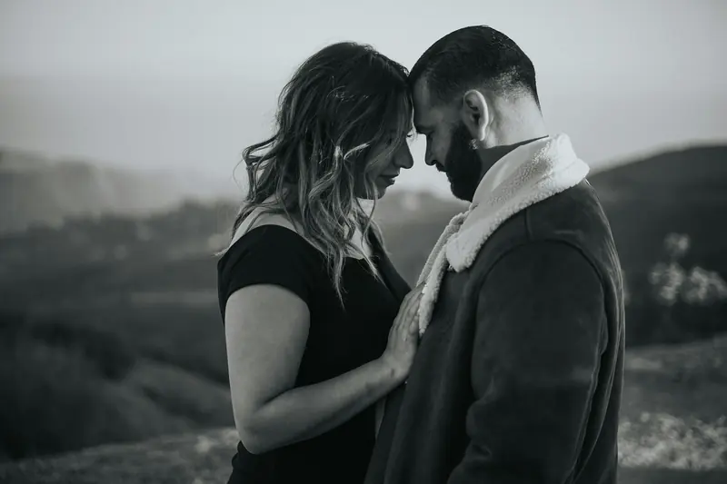 A couple resting their foreheads together above the hills
