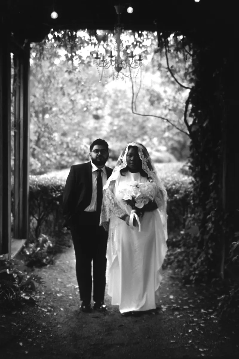A couple walking out of a garden under hanging lights
