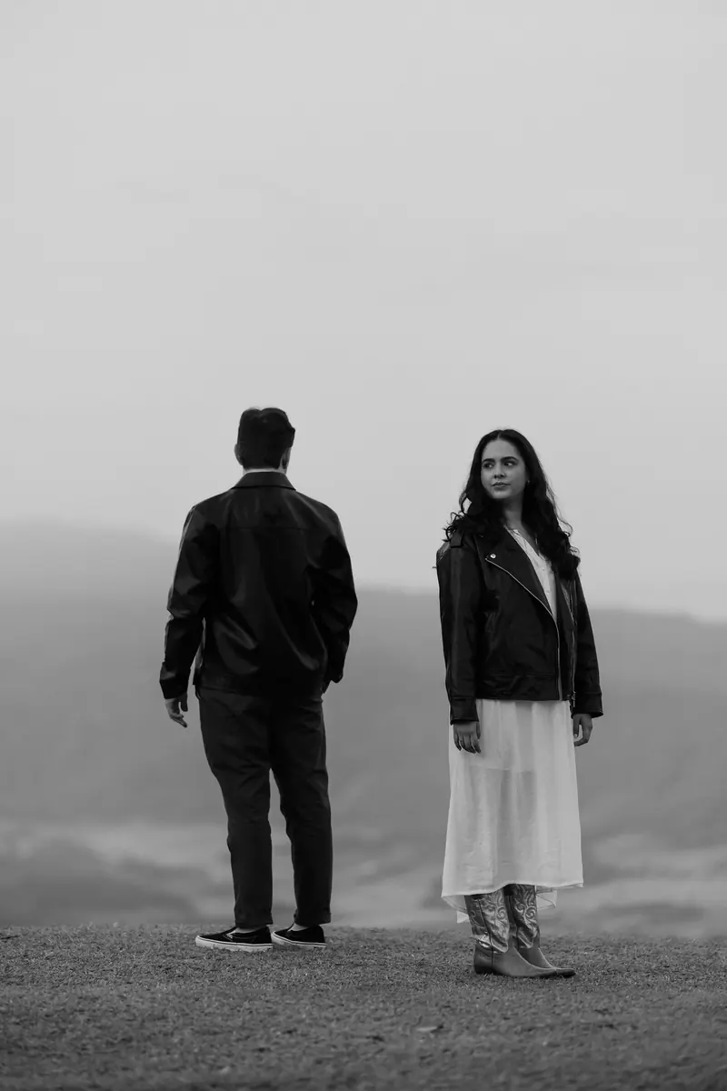 A couple standing apart on a grassy hilltop in the fog