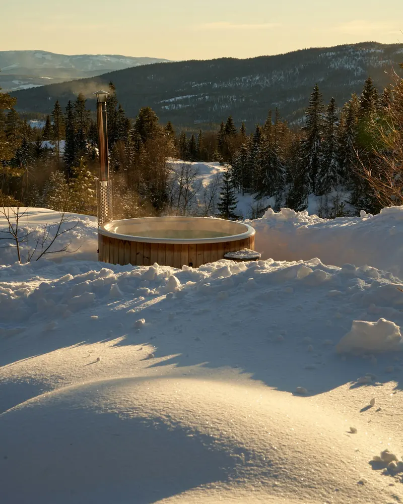 A wooden hot tub in the snow above a valley