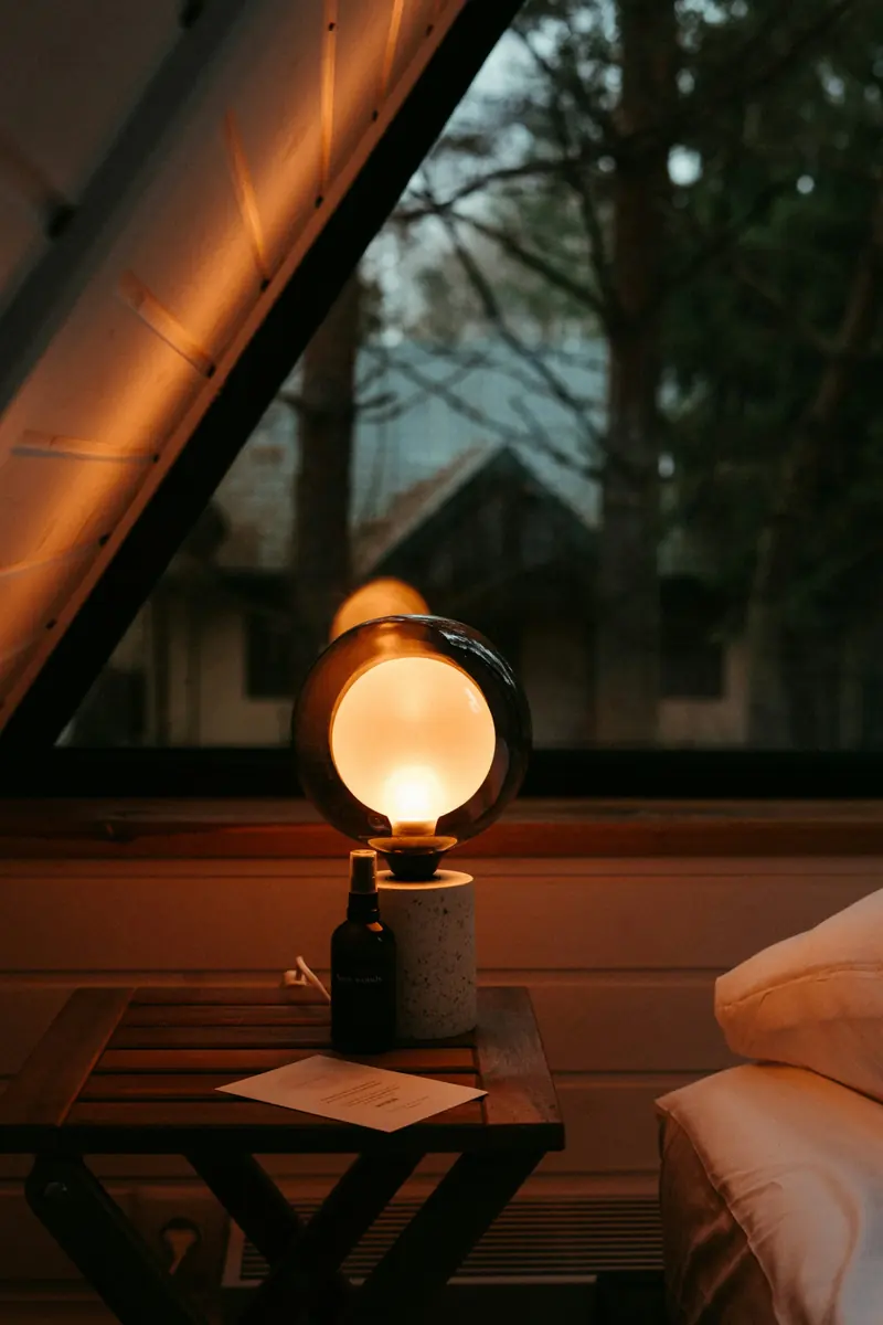 A round lamp glowing on a wooden bedside table