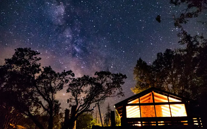 A lit cabin under the Milky Way