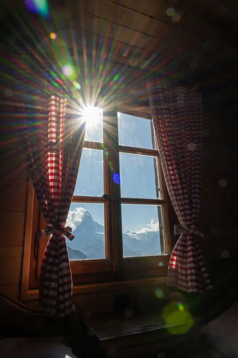 Sun coming through a cabin window with a mountain view