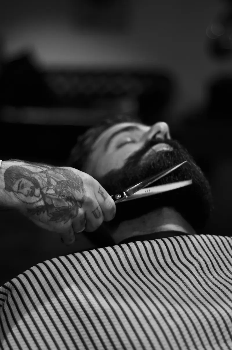 A barber trimming a beard with scissors