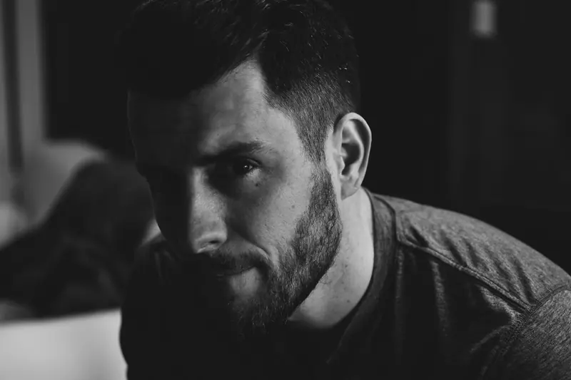 A man with a fresh cut sitting in a dark room