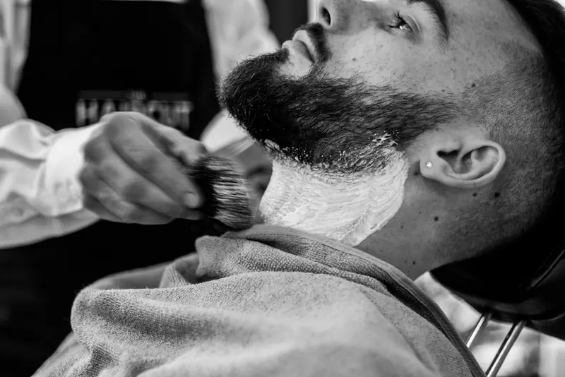 A barber shaving a customer's beard
