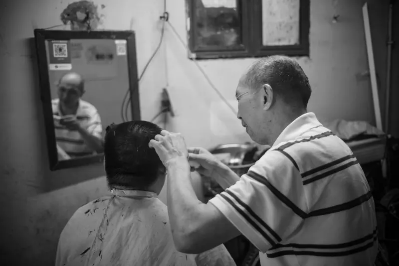 A barber cutting hair by the mirror