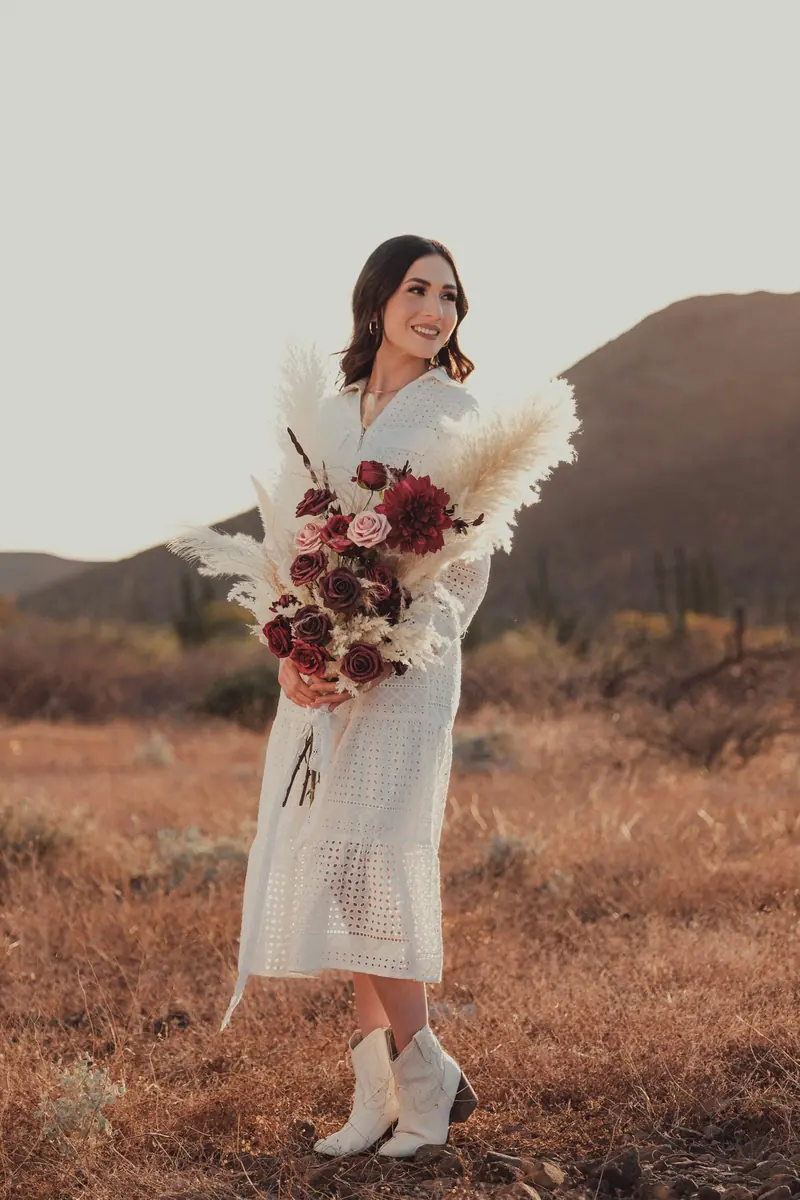 A woman in a white dress holding a big bouquet in the hills