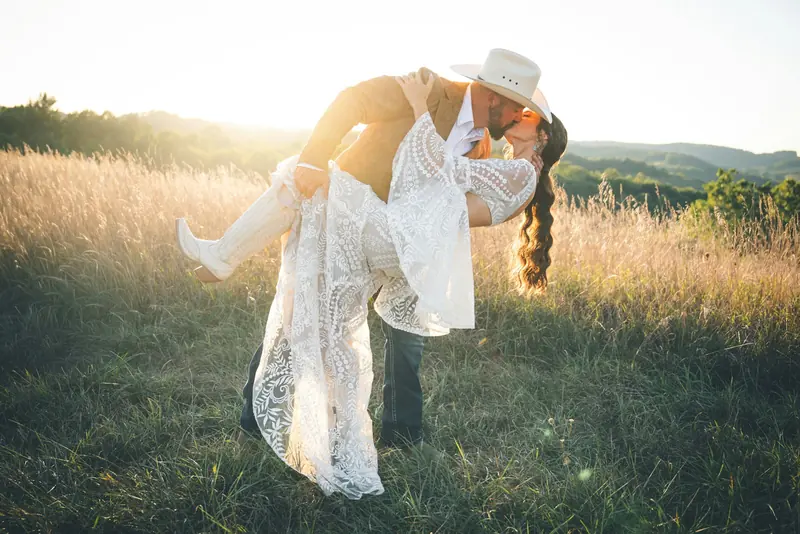 A couple kissing in tall grass in warm evening light