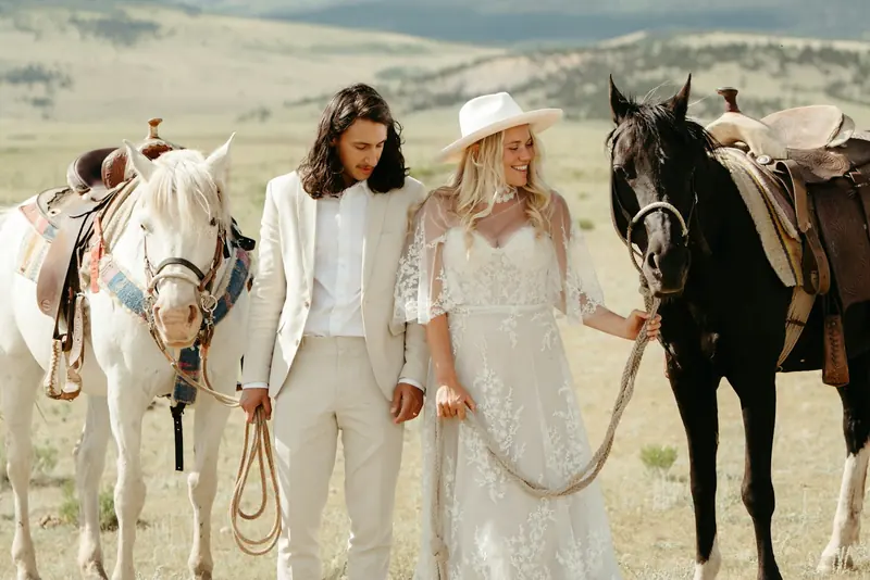 A couple standing with their saddled horses