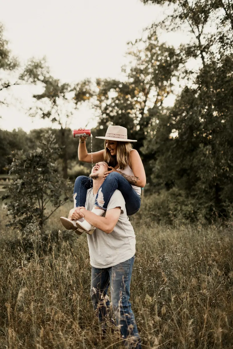 A man carrying a woman piggyback through a field