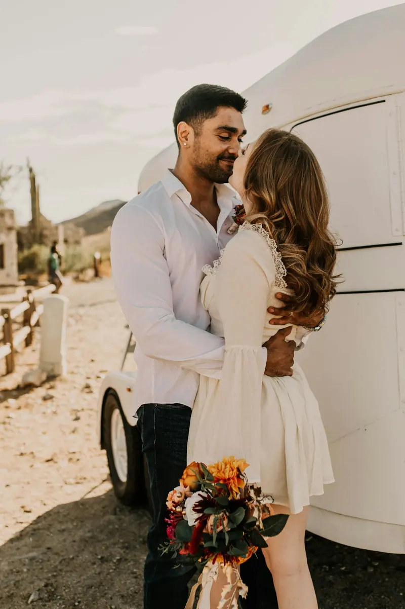 A couple kissing beside a vintage trailer