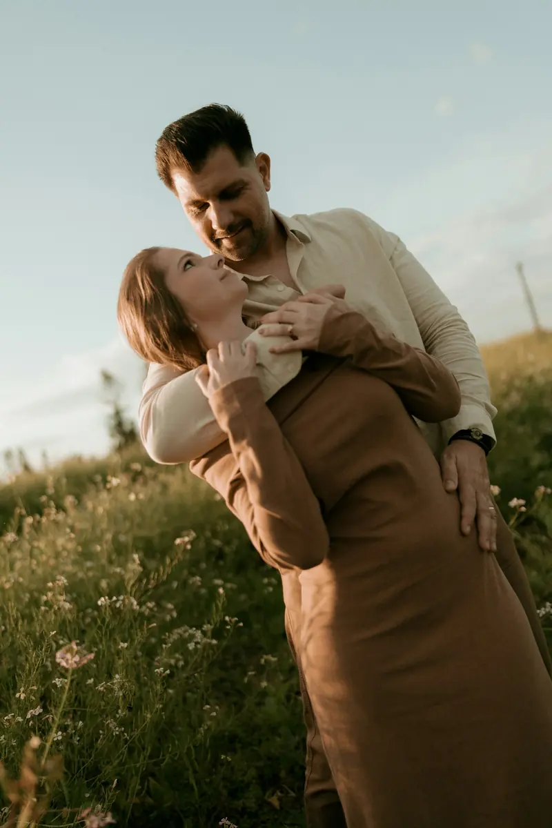 A couple holding each other in a field of wildflowers at golden hour
