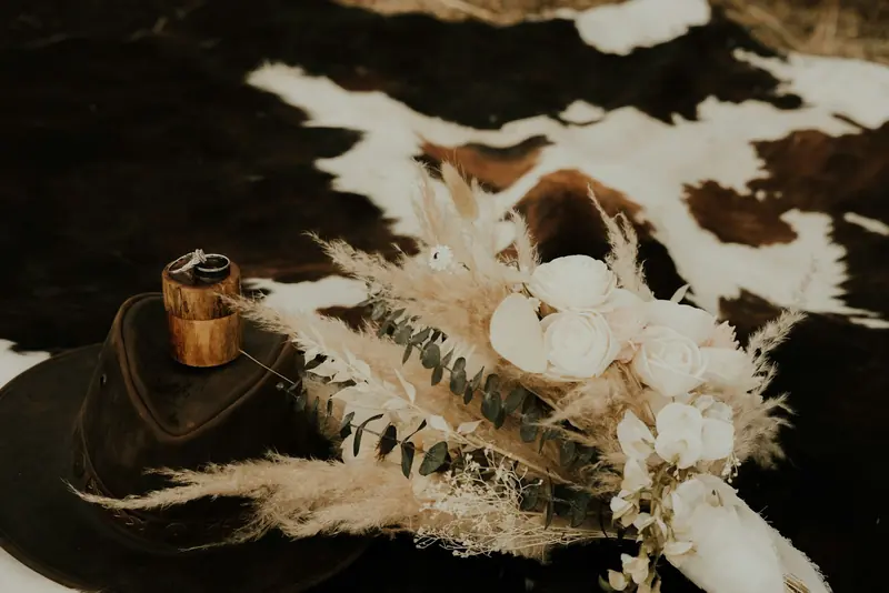 A felt hat and dried flowers on a cowhide