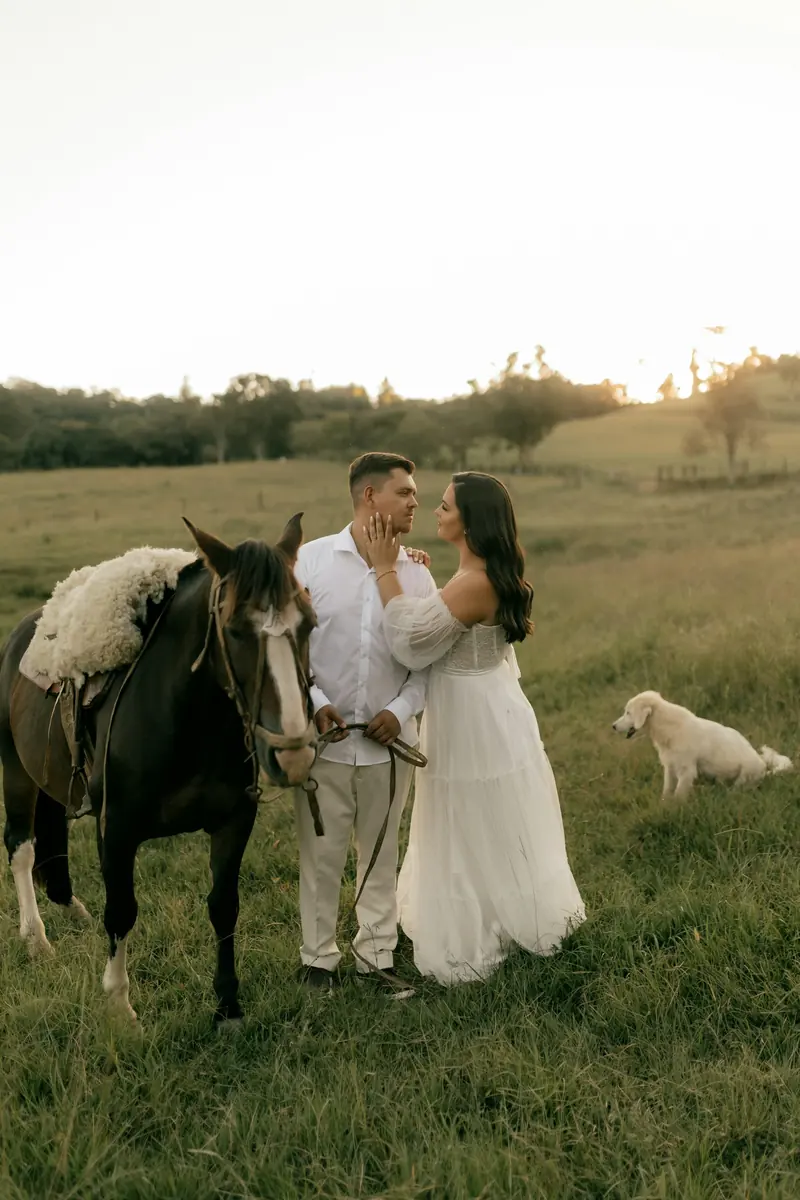 A couple with their horse and dog in a grassy field