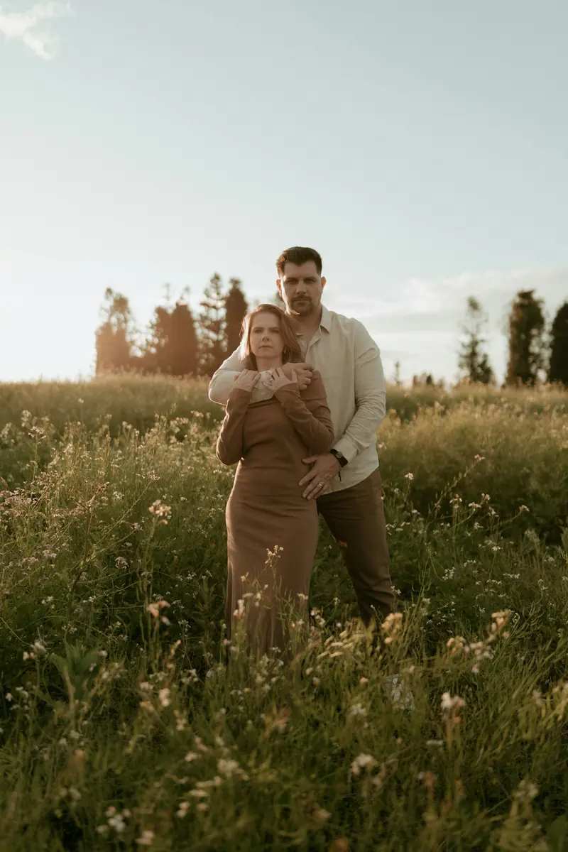 A couple hugging in a sunlit field of wildflowers