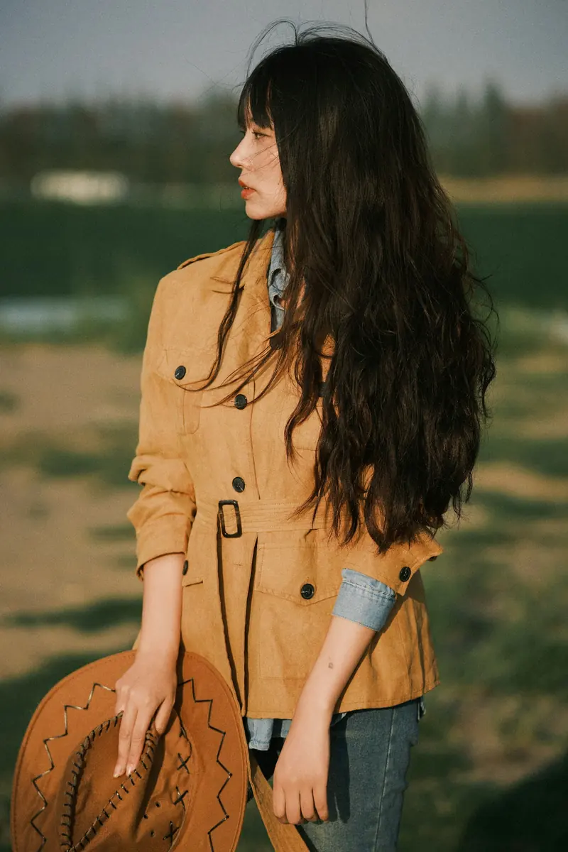 A woman in a tan jacket holding a cowboy hat