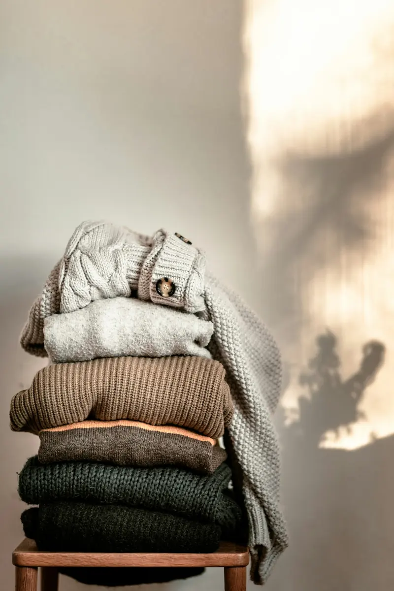 Sweaters stacked on a wood chair