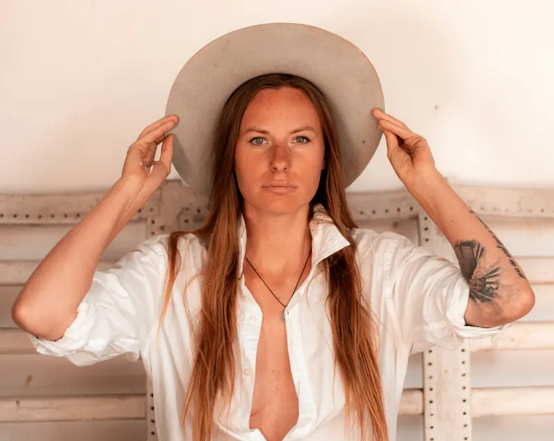 A woman in a white shirt and brown hat