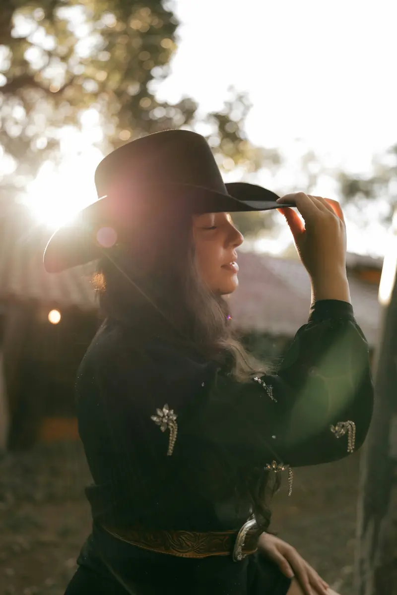 A woman in a cowboy hat with the sun behind her